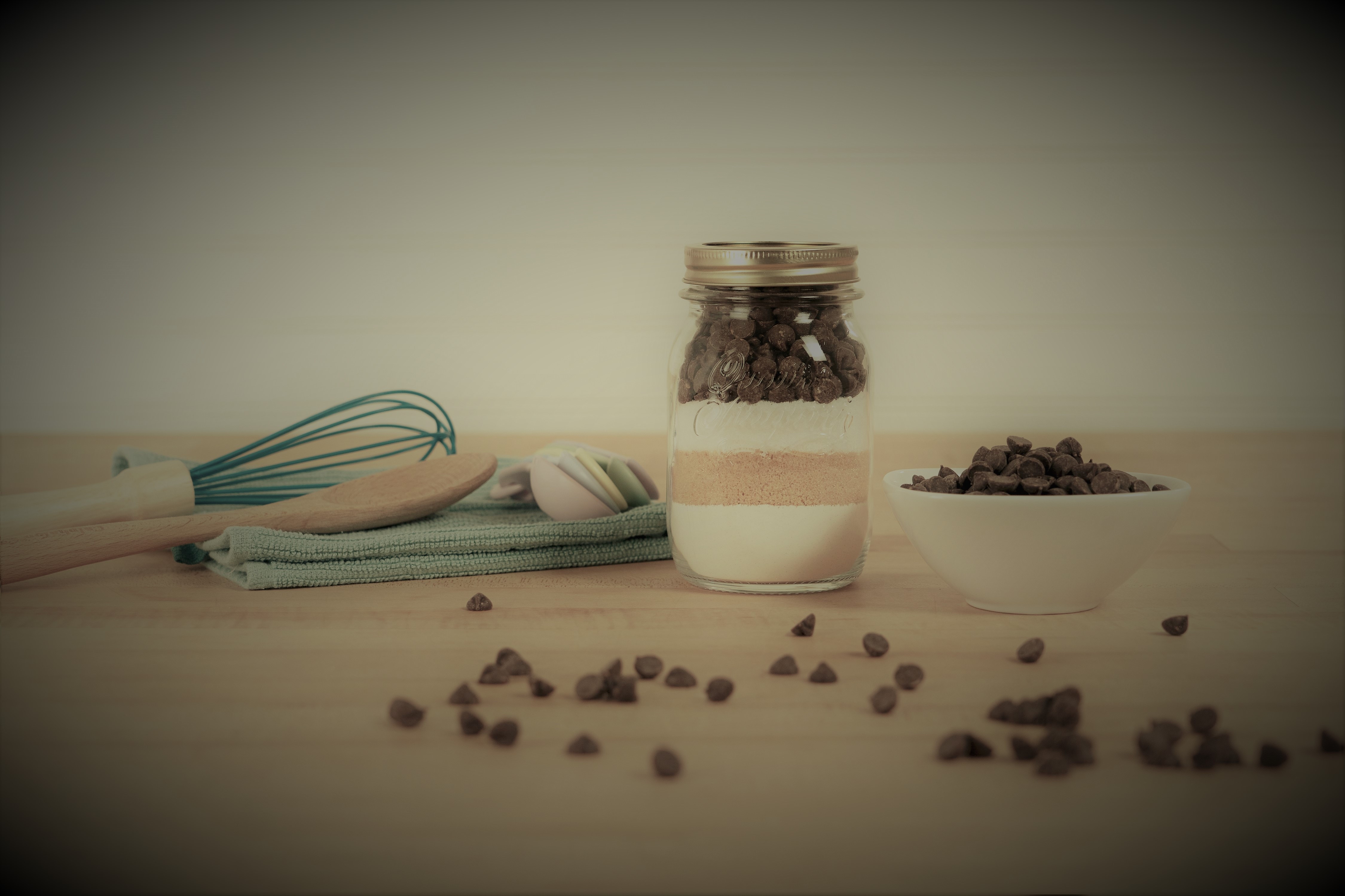 Imagem de uma mesa com utensílios para cozinhar, assim como alguns produtos para montar uma receita.